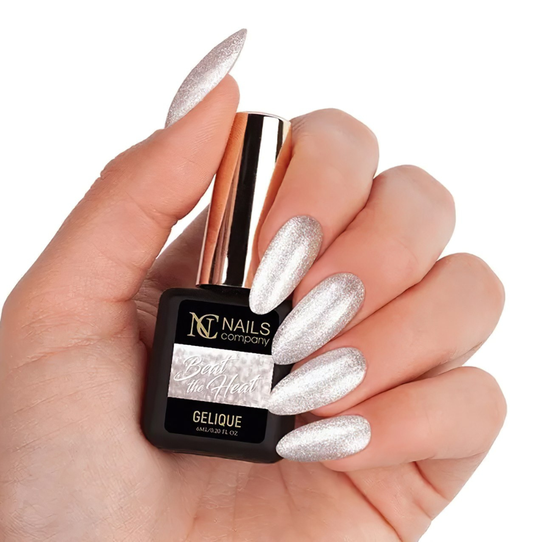 Main tenant le flacon de vernis semi-permanent Beat The Heat de Nails Company, champagne pailleté visible sur ongles