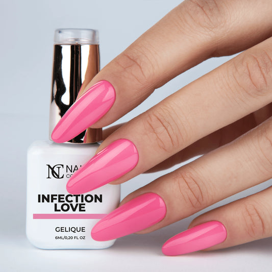 Main tenant le flacon de vernis semi-permanent Infection Love de Nails Company, teinte rose pastel visible sur l’ongle