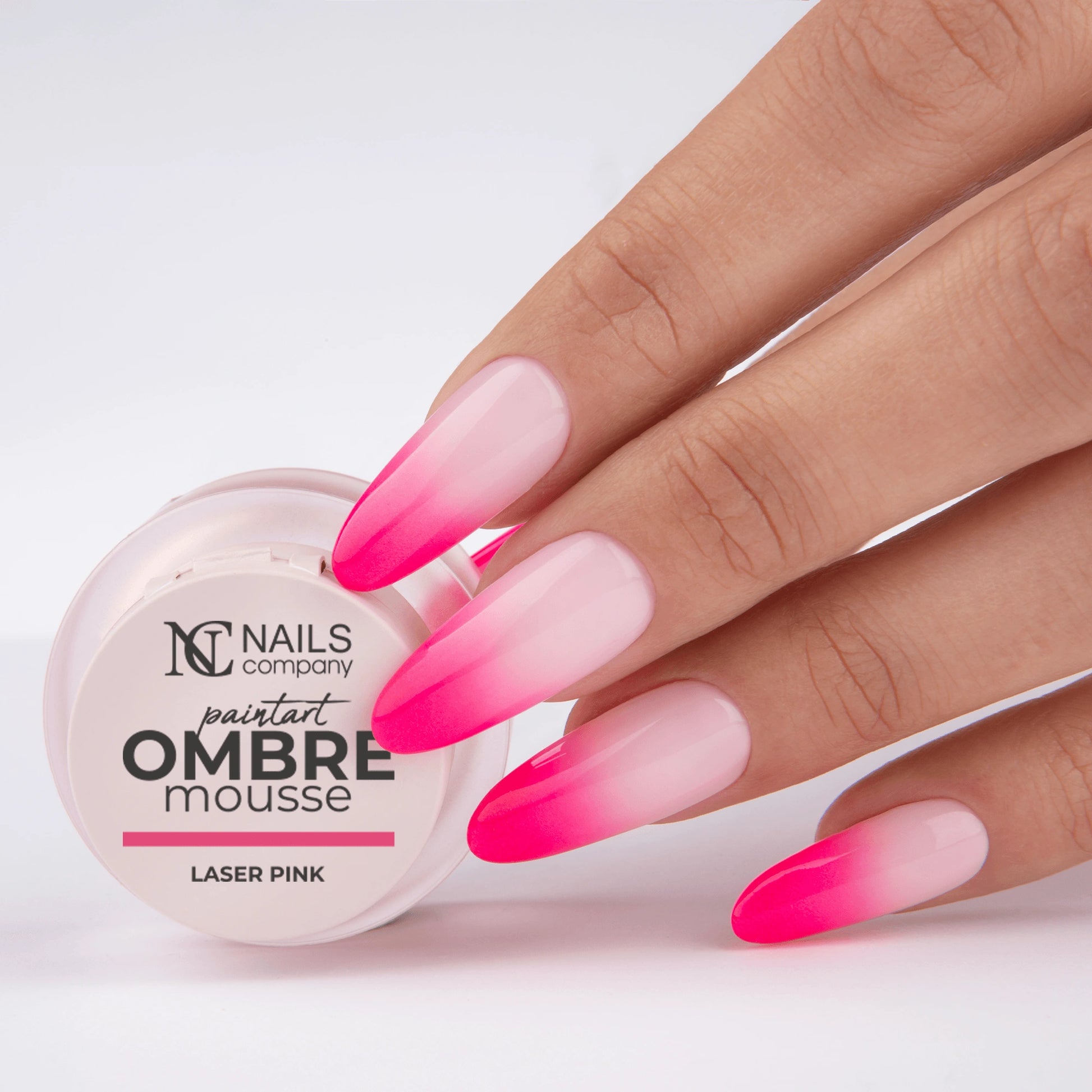 Main tenant le pot de Paintart Ombre Mousse Laser Pink de Nails Company avec le produit appliqué sur les ongles