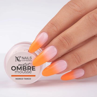 Main tenant le pot de Paintart Ombre Mousse Mango Tango de Nails Company avec le produit appliqué sur les ongles