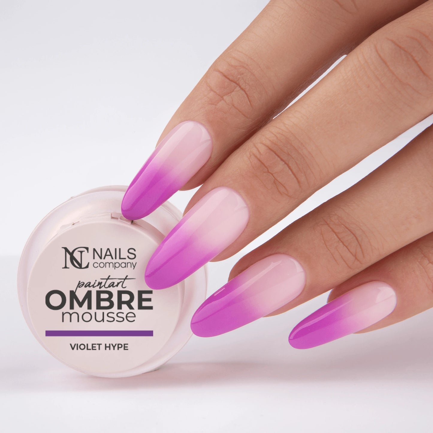 Main tenant le pot de Paintart Ombre Mousse Violet Hype de Nails Company avec le produit appliqué sur les ongles