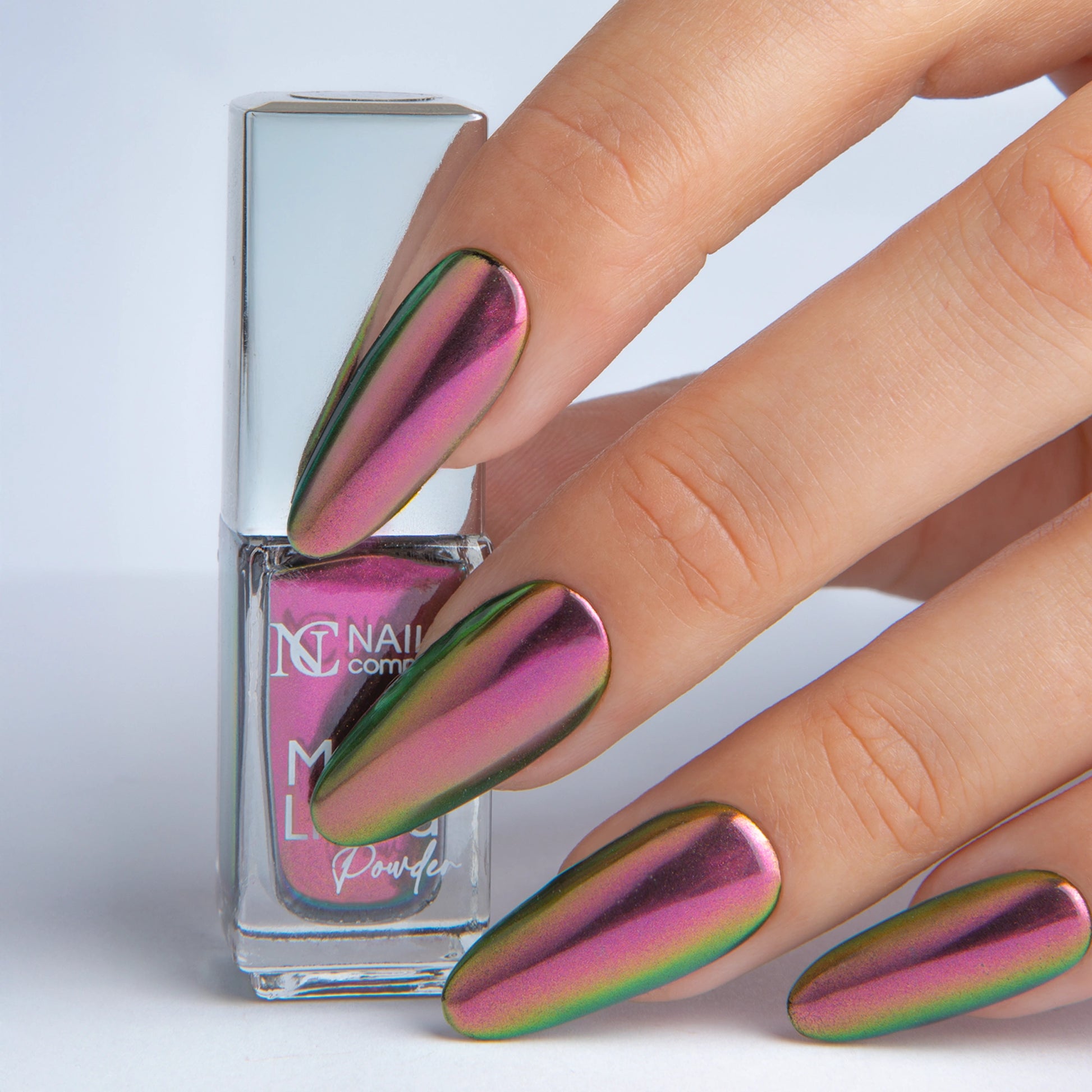 Main tenant le Mirror Liquid Powder 003 Nails Company avec effet chrome rubis violet visible.