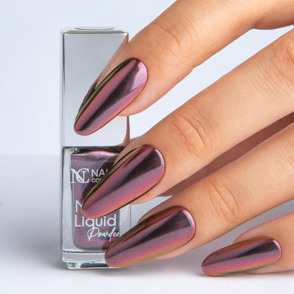 Main tenant le Mirror Liquid Powder 006 Nails Company avec effet chrome bordeaux prune visible.