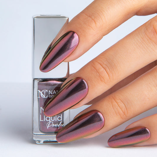 Main tenant le Mirror Liquid Powder 006 Nails Company avec effet chrome bordeaux prune visible.