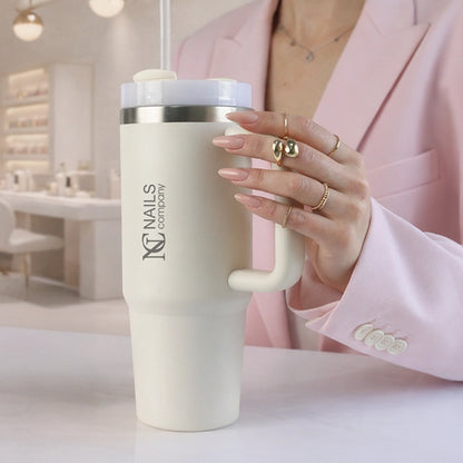 Main tenant le Mug Isotherme NC Girl Nails Company blanc avec poignée et paille intégrée.