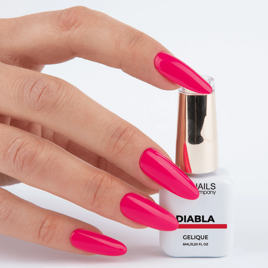 Vernis semi permanent Diabla Nails Company tenu en main avec couleur rose fuchsia intense visible.