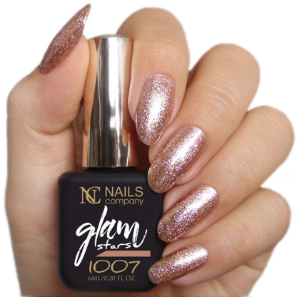 Main tenant le flacon de vernis semi-permanent Glam Stars 1007 de Nails Company, doré pailleté visible sur les ongles
