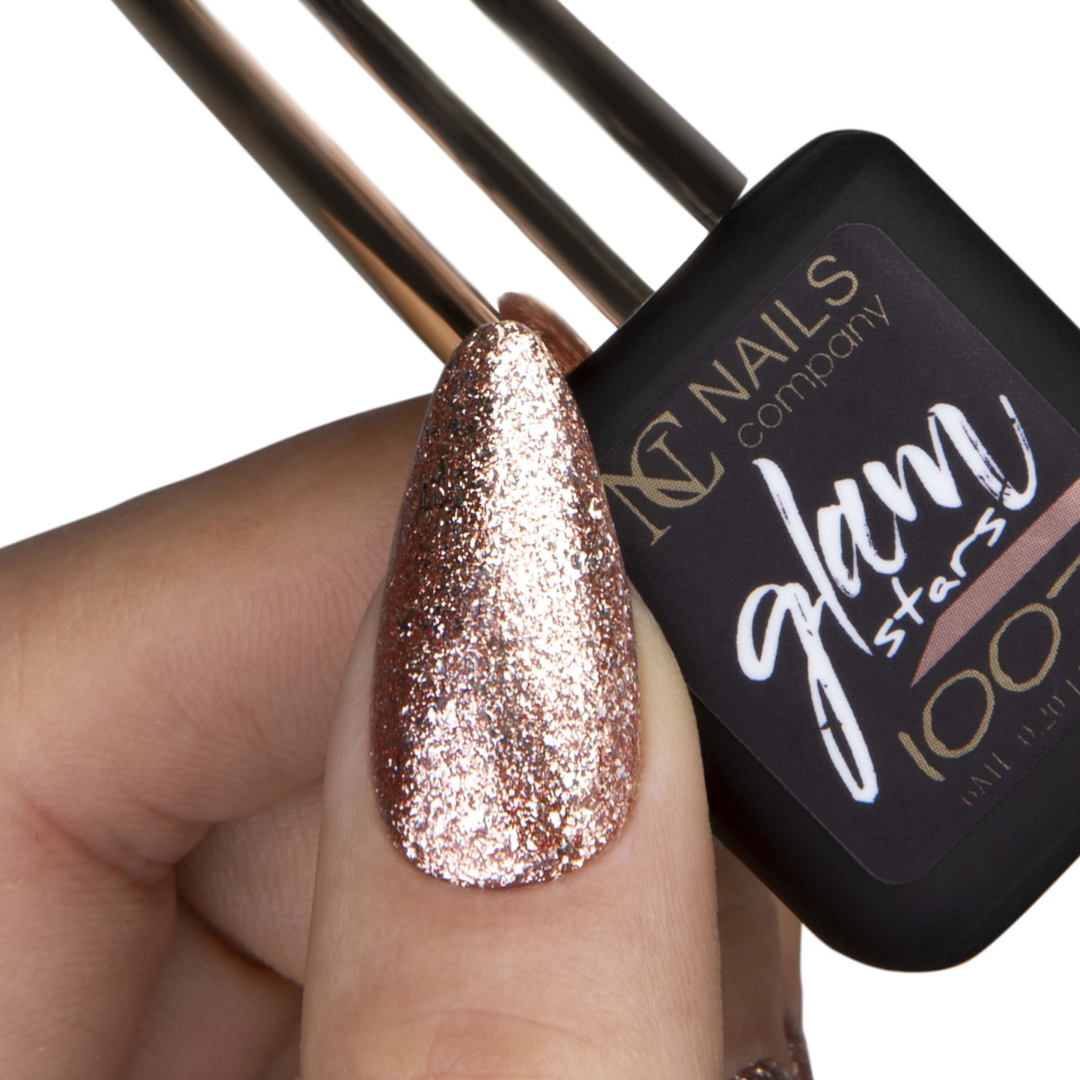 Main tenant le flacon de vernis semi-permanent Glam Stars 1007 de Nails Company, pouce avec doré pailleté apparent