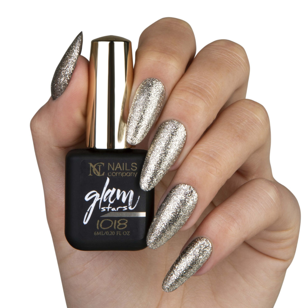 Main tenant le flacon de vernis semi-permanent Glam Stars 1018 de Nails Company, doré clair pailleté visible sur les ongles