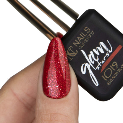 Main avec pouce tenant le flacon de vernis semi-permanent Glam Stars 1019 de Nails Company, collection Glam Stars