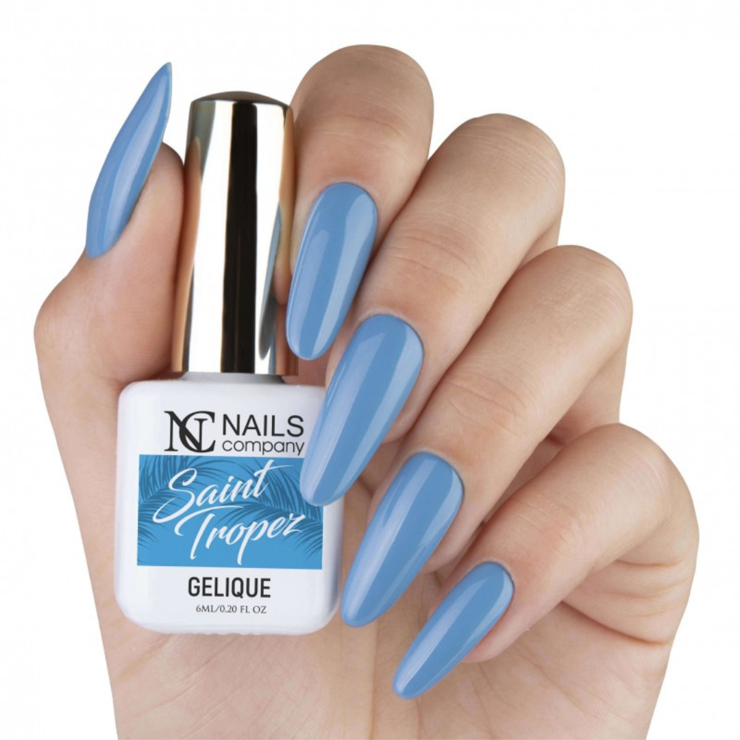 Main tenant le flacon de vernis semi permanent Saint Tropez de Nails Company, bleu clair visible sur les ongles