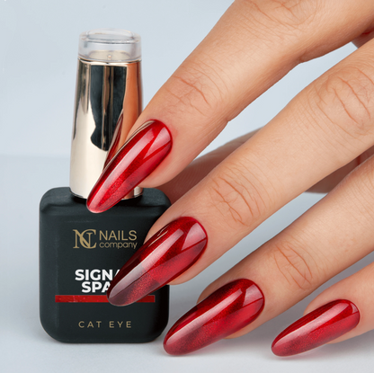 Main tenant le flacon de vernis semi-permanent Signal Spam de Nails Company, rouge orangé cat eye visible sur l’ongle