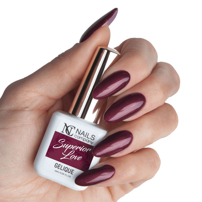 Main tenant le flacon de vernis semi-permanent Superior Love de Nails Company, rouge foncé enrichi de fines particules