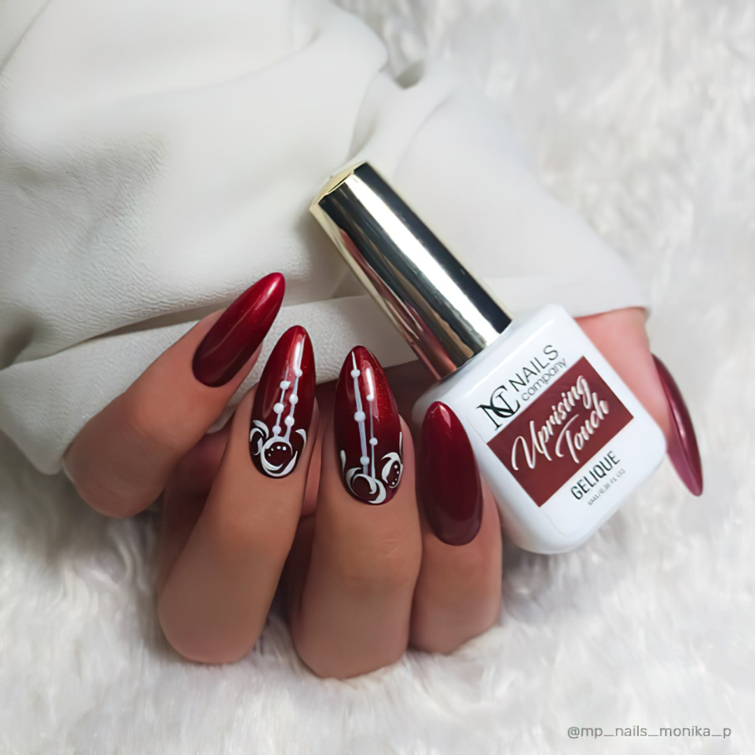 Flacon de vernis semi-permanent Uprising Touch de Nails Company tenu en main, teinte rouge bordeaux à particules rouges