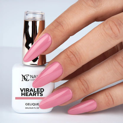 Main tenant le flacon de vernis semi-permanent Viraled Hearts de Nails Company, teinte rose pêche pastel visible